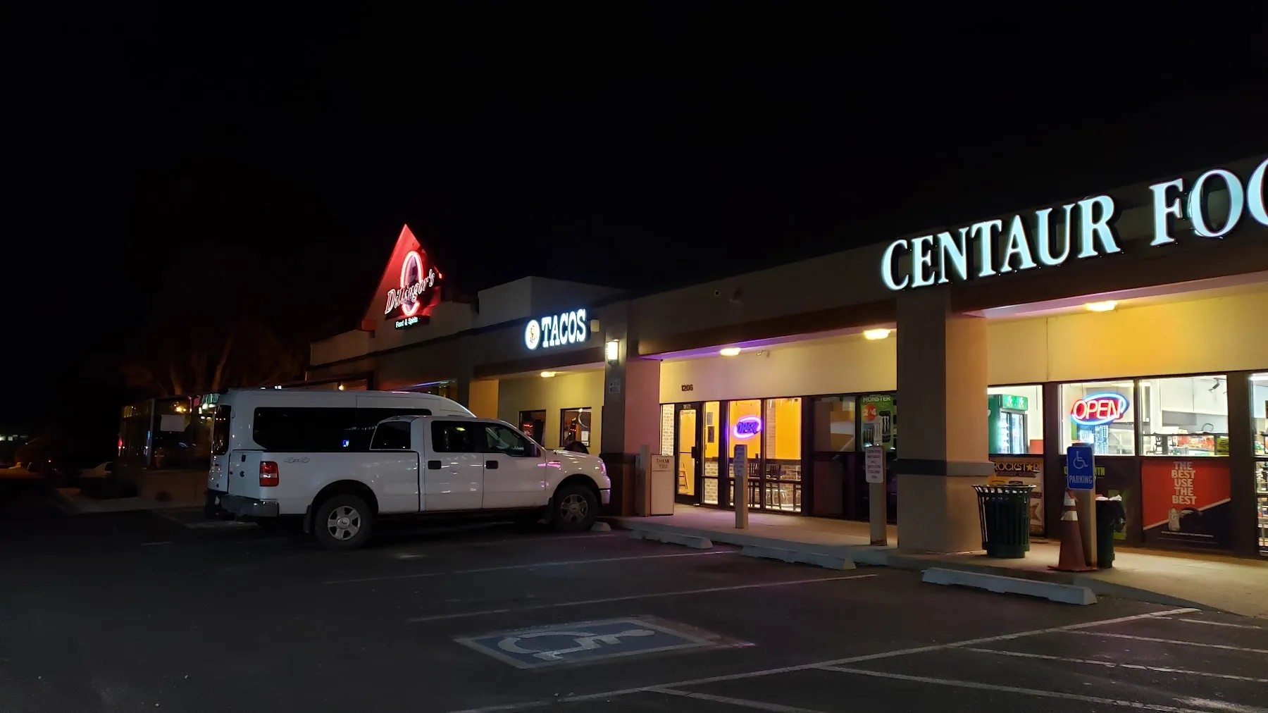 Tacos Ay Ay Ay storefront lit up at night with its red TACOS sign in the Centaur Village plaza