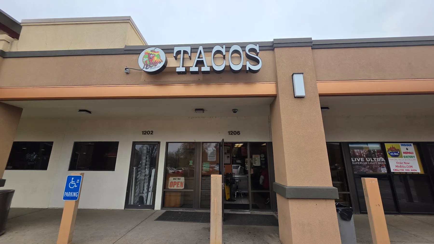 Daytime view of the Tacos Ay Ay Ay storefront at 1206 with the TACOS sign and an open door